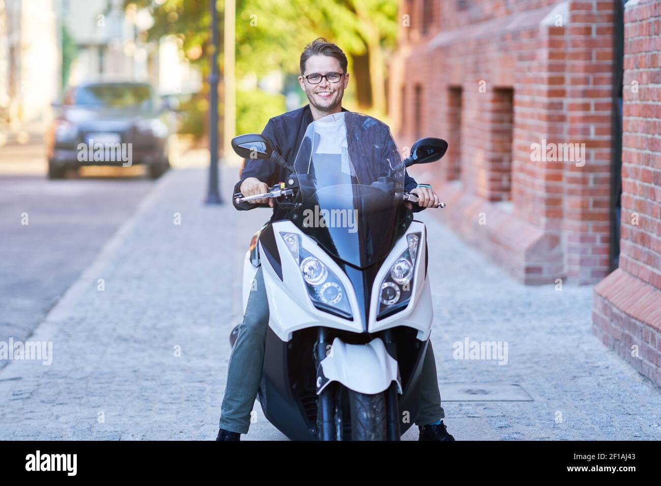 Heureux homme à bord d'un scooter dans la ville sur un jour ensoleillé Banque D'Images