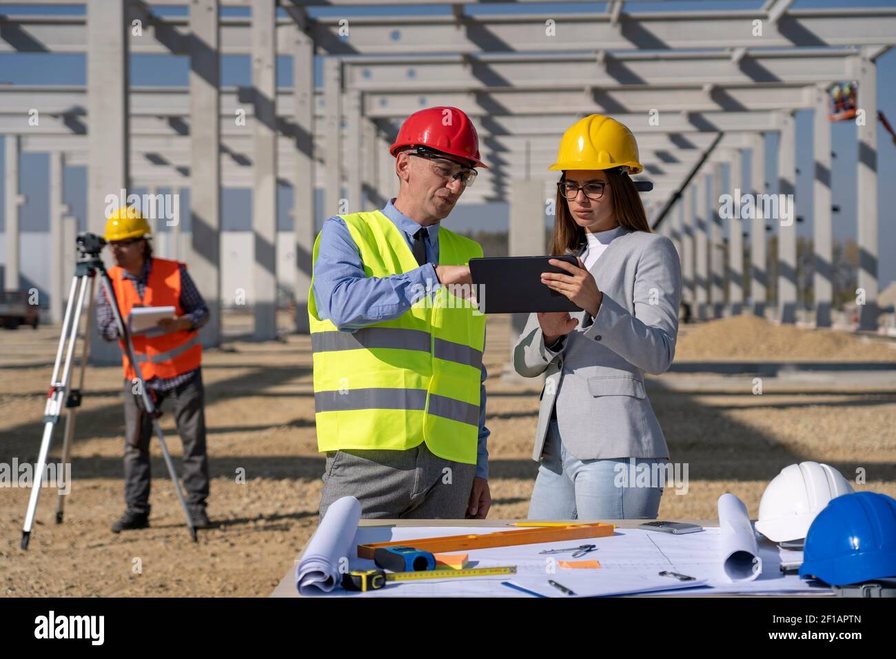 Jeune femme architecte avec tablette et homme d'affaires mature Réunion sur le site de construction. Concept de relation d'affaires et de travail d'équipe. Banque D'Images