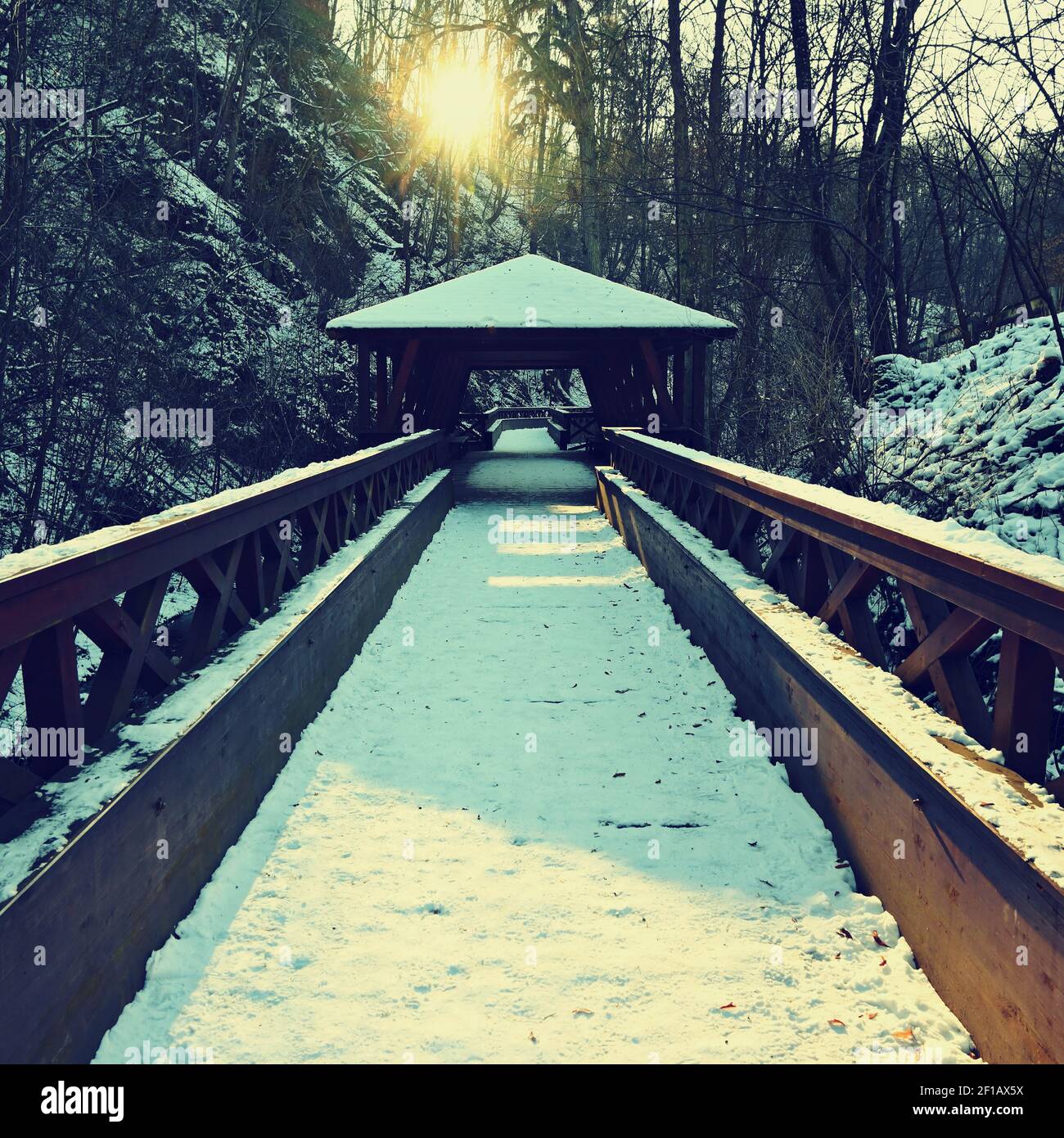 Magnifique pont en bois enneigé avec un chemin pour la randonnée. Hiver avec neige et soleil. Banque D'Images