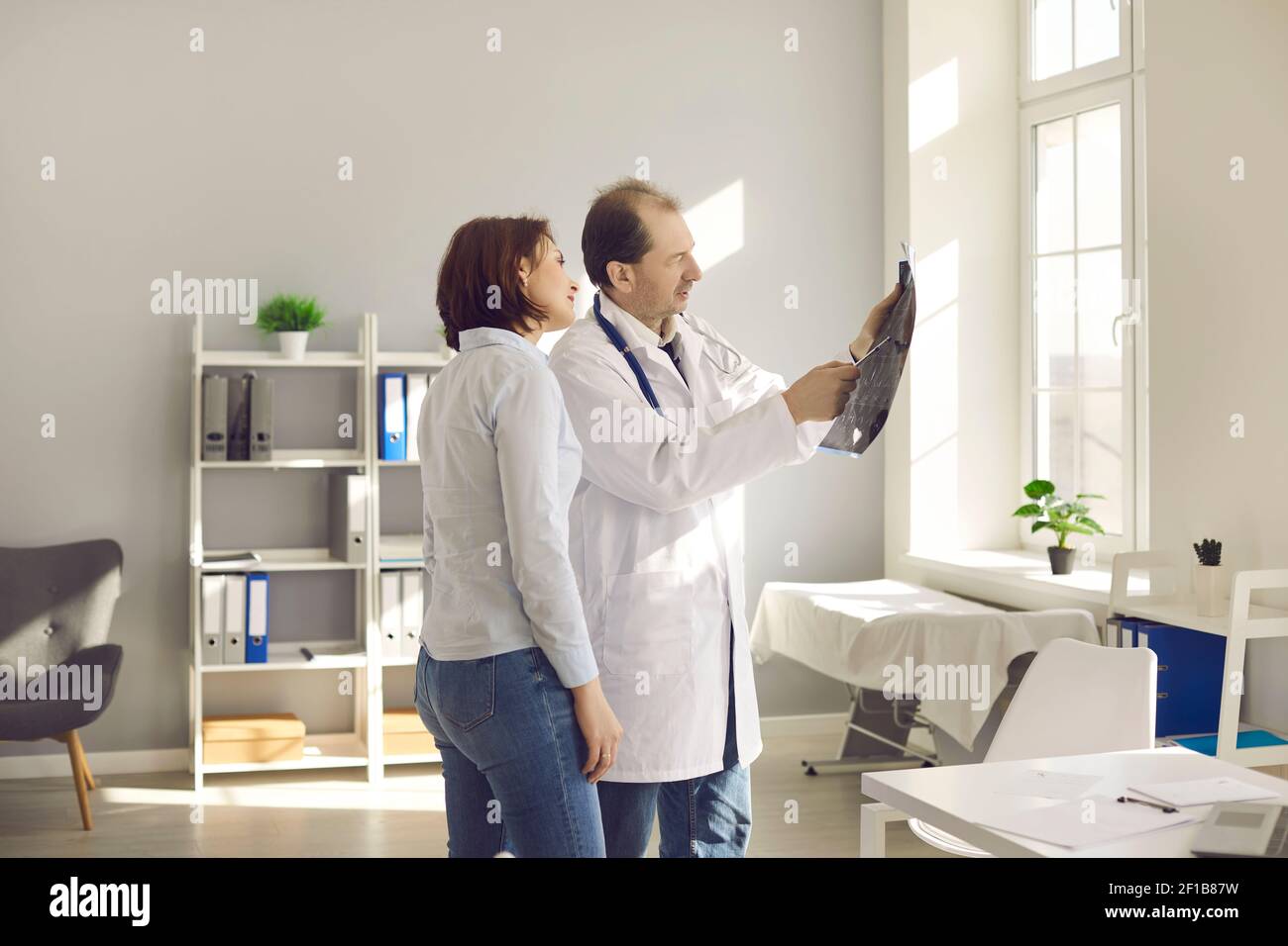 Femme écoutant les explications du médecin tout en regardant une IRM, une tomodensitométrie ou une radiographie Banque D'Images