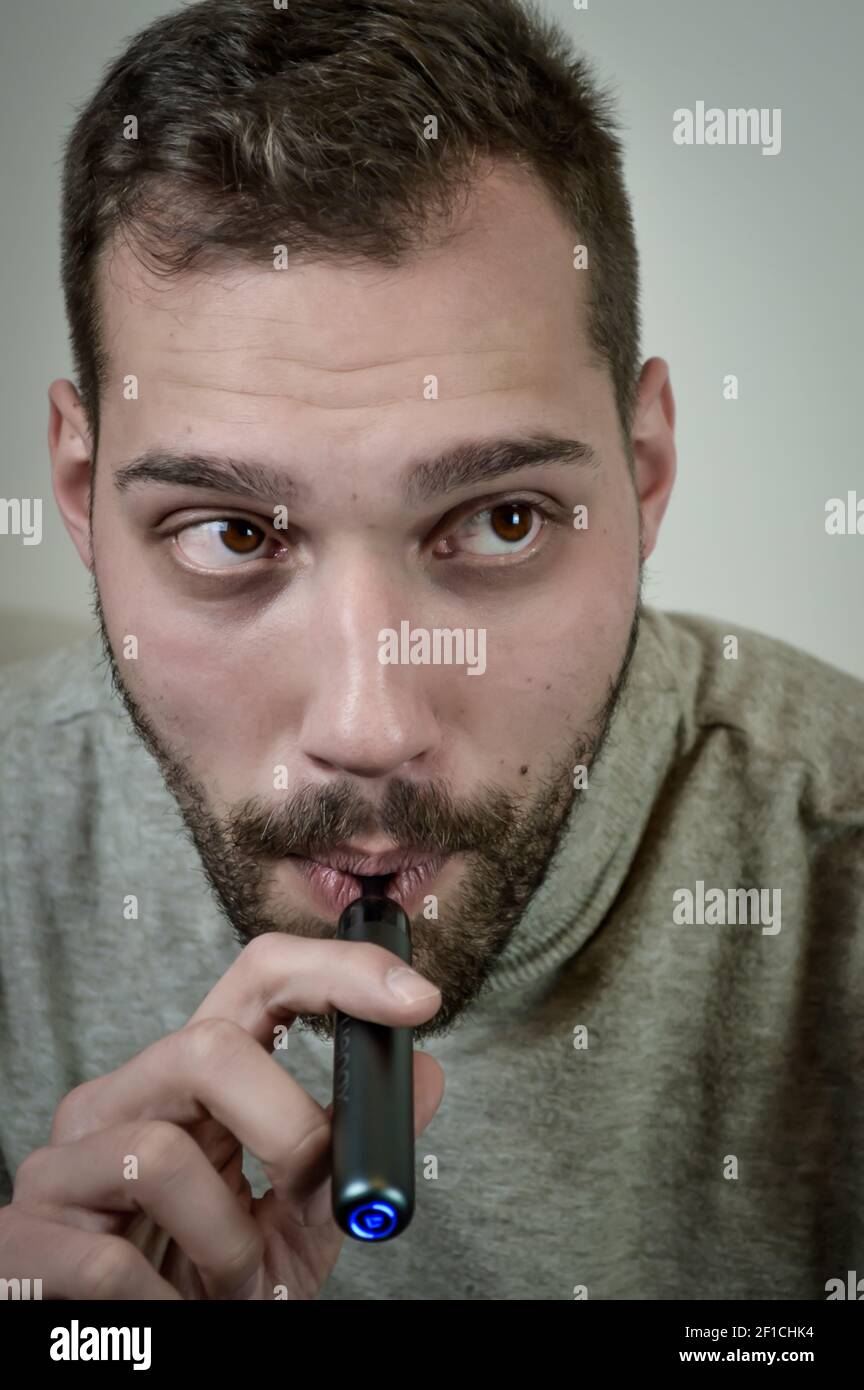 Portrait d'un jeune barbu qui fume une cigarette électronique, gros plan Banque D'Images