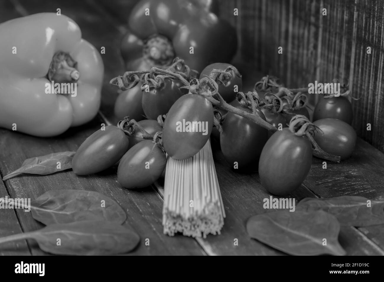Noir et blanc vue rapprochée des spaghetti de pâtes crues sur fond de bois.légumes frais biologiques avec pâtes non cuites, concept alimentaire sain. Banque D'Images