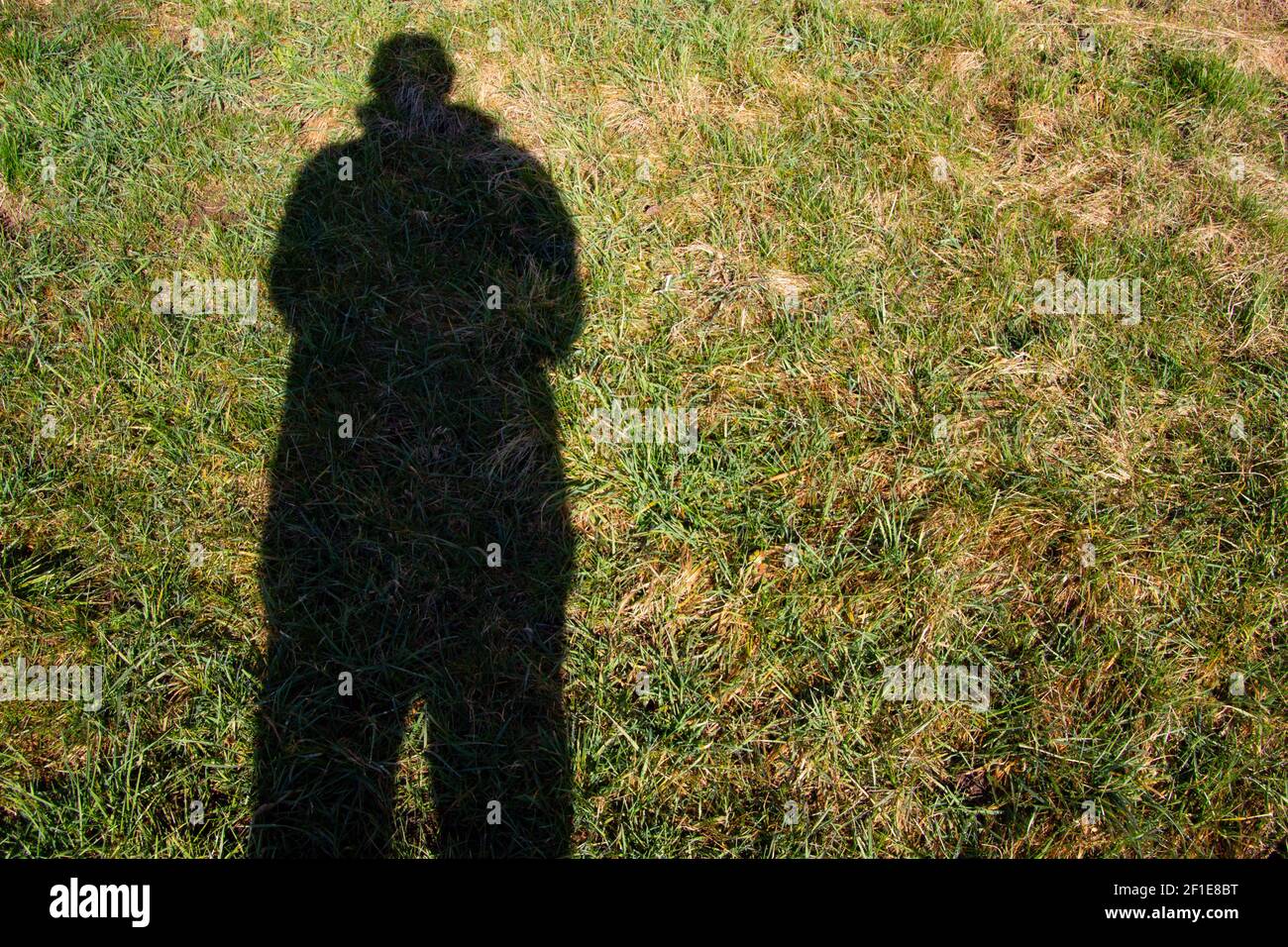 Ombre haute sombre d'un homme avec un manteau dans le herbe avec espace de copie Banque D'Images