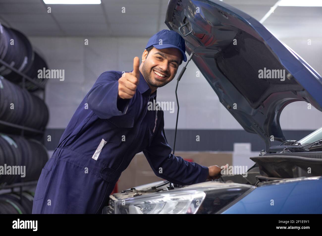 Mécanicien de voiture debout à côté d'une voiture entretenue AVEC UN bravo Banque D'Images