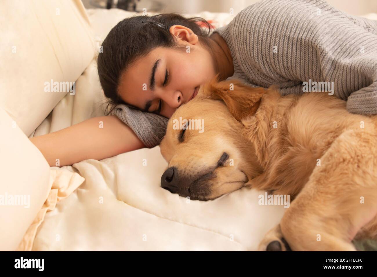 UN CHIEN ET UN ADOLESCENT DORMANT ENSEMBLE SUR LE LIT Banque D'Images