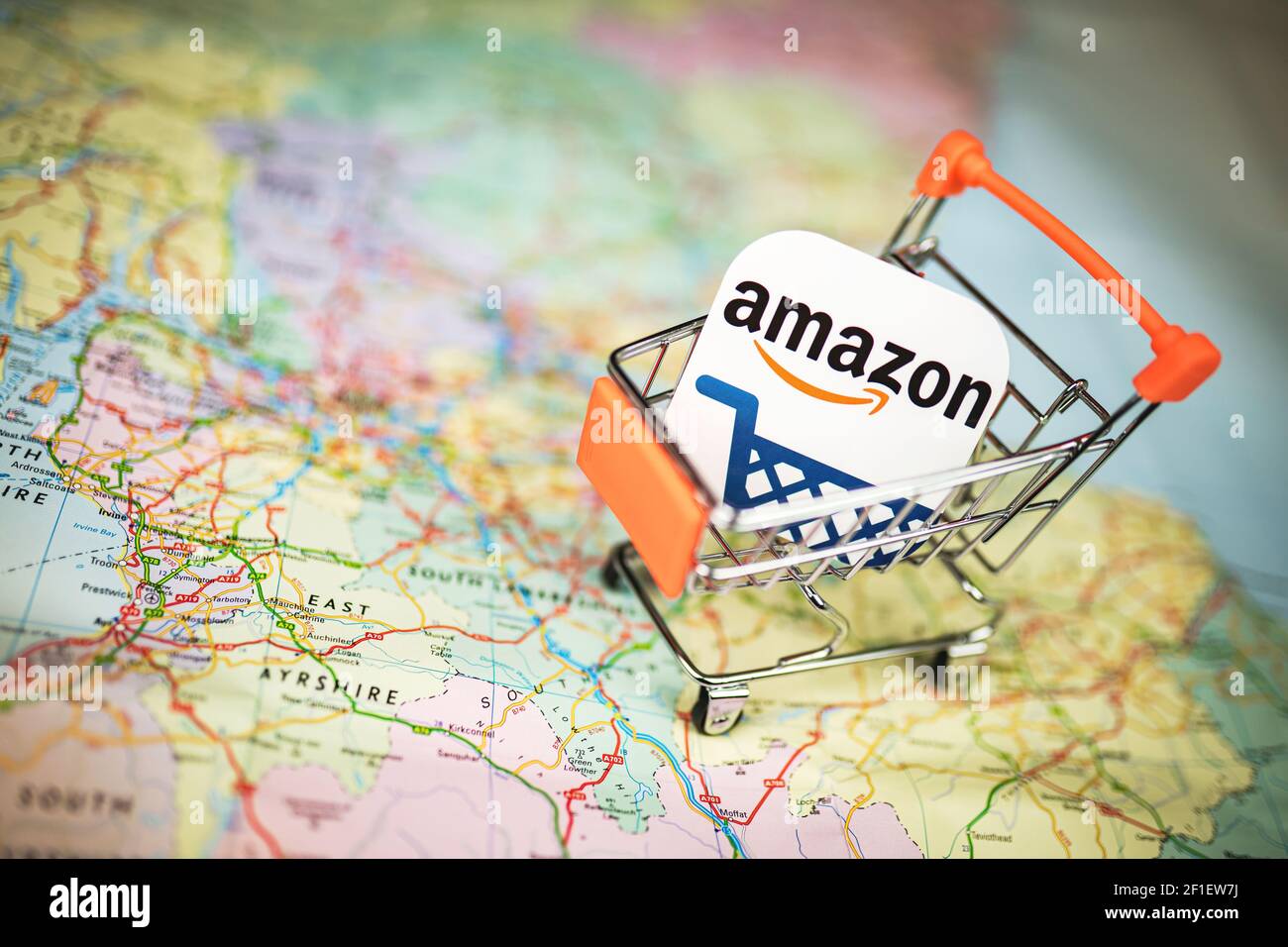 Logo Amazon dans un petit chariot au-dessus de la carte du Royaume-Uni. Achat en ligne, achat Amazon, concept d'e-commerce Banque D'Images