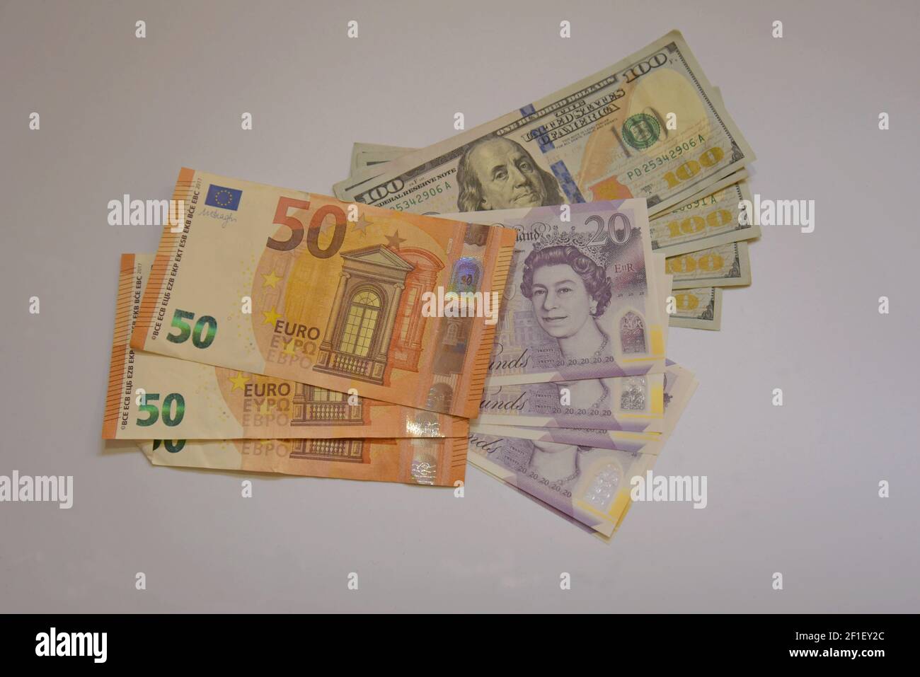 Une sélection de billets en livres sterling, en euros et en dollars américains sur fond blanc Banque D'Images