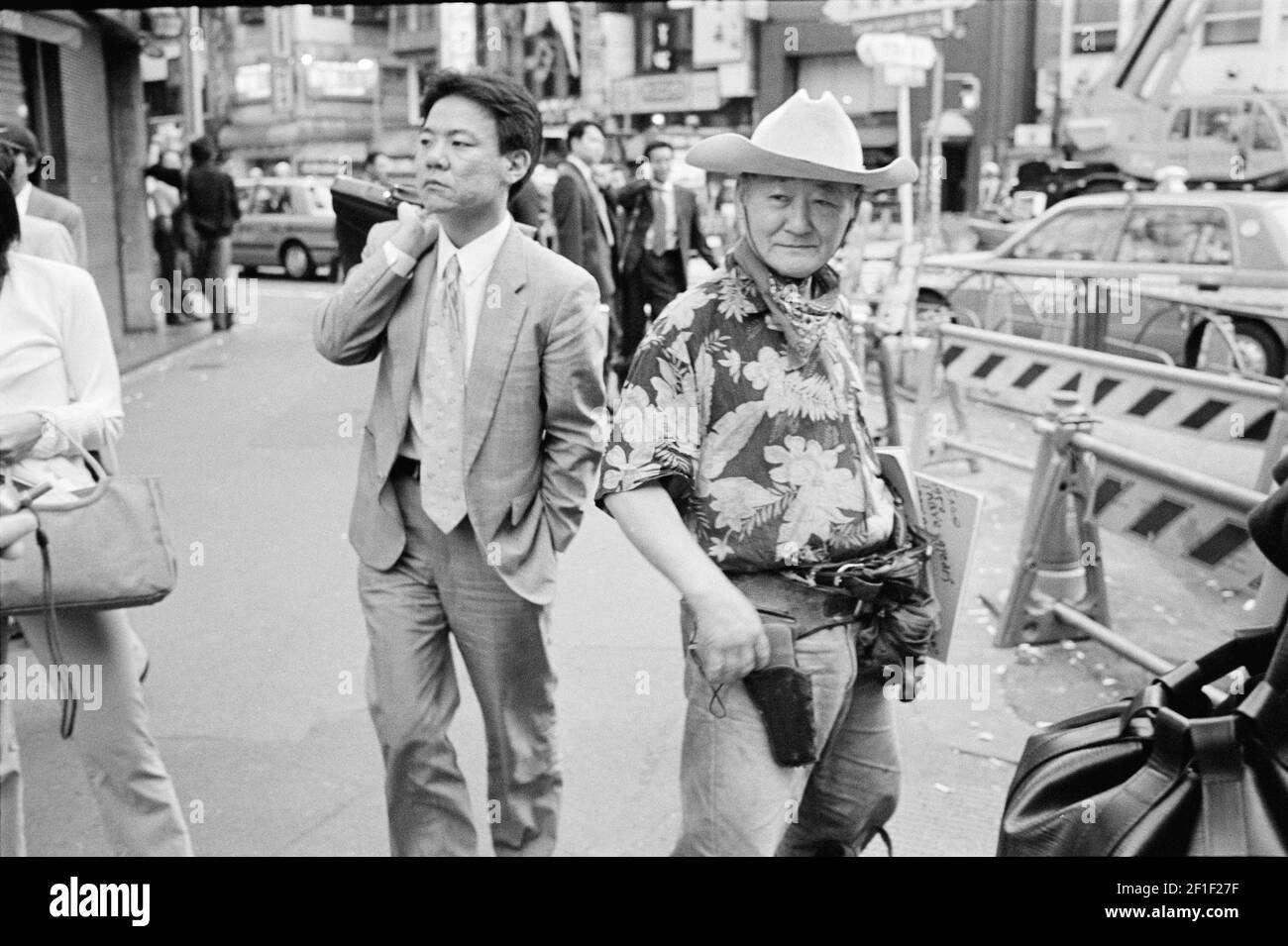Un cowboy à Tokyo : un homme habillé d'un costume de cowboy debout dans le quartier shinjuku pendant que l'homme d'affaires va travailler, Tokyo , Japon . Banque D'Images