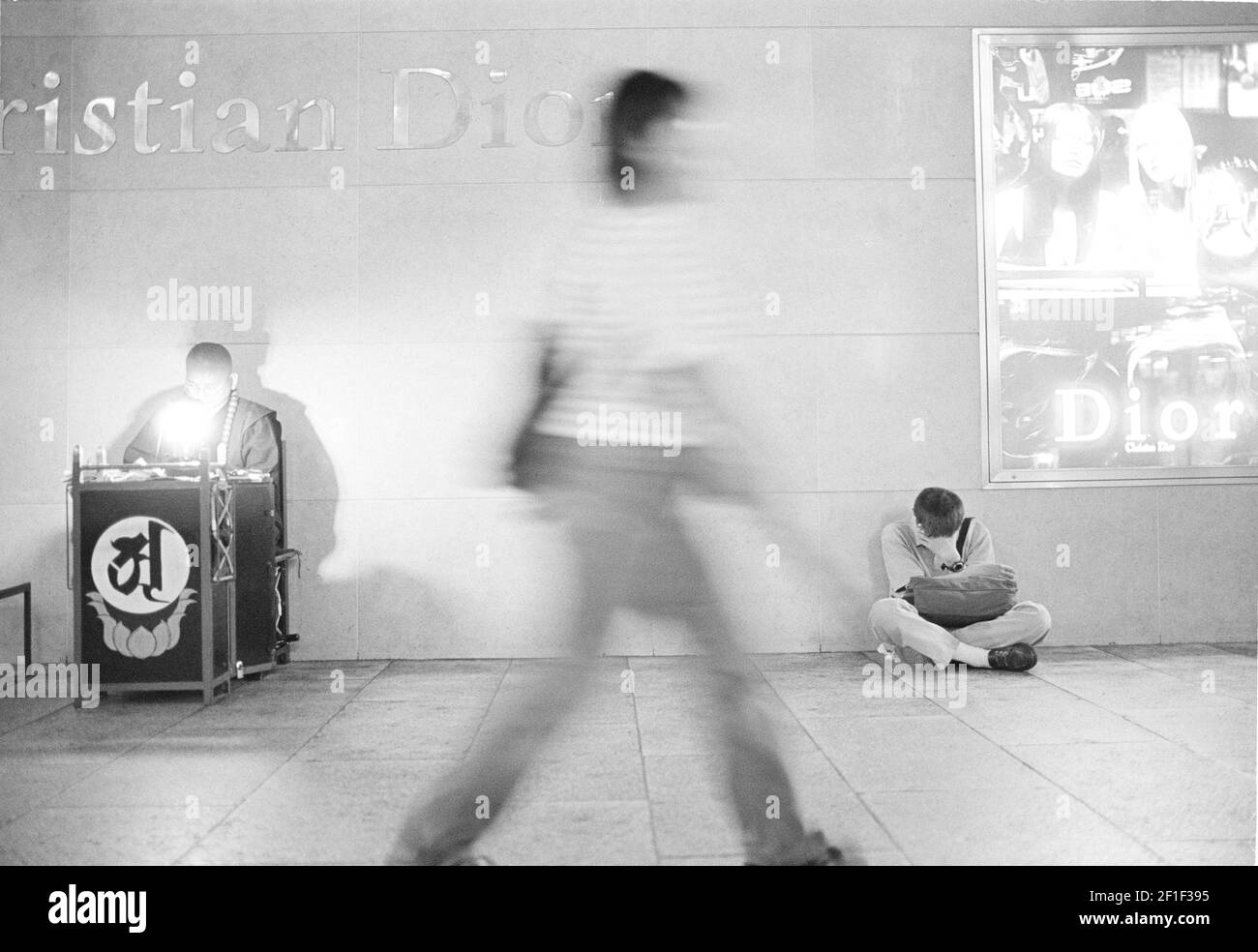 Femme passant devant un homme sans domicile à la station de métro de Tokyo , Tokyo , Japon . Banque D'Images