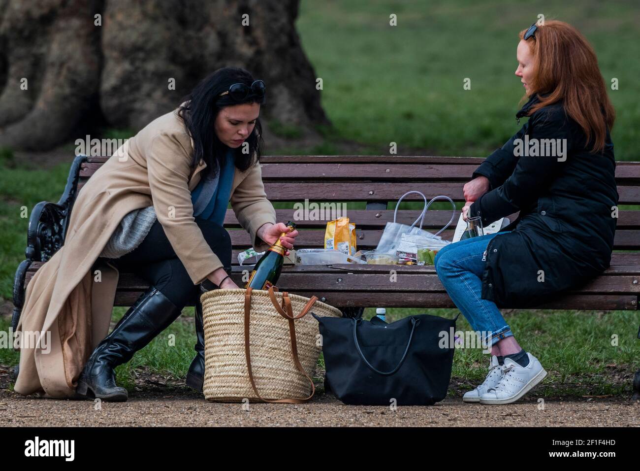 Londres, Royaume-Uni. 8 mars 2021. Deux amies se rencontrent pour un pique-nique avec du champagne de fête (qu'elles ont d'abord du mal à ouvrir) car il est permis aujourd'hui pour la première fois cette année. Il est sec mais froid et les gens sont à la rencontre d'amis car ils profitent des restrictions légèrement assouplies aujourd'hui. La vie en plein air sur Clapham commune comme Lockdown 3 commence à se détendre un peu . Crédit : Guy Bell/Alay Live News Banque D'Images