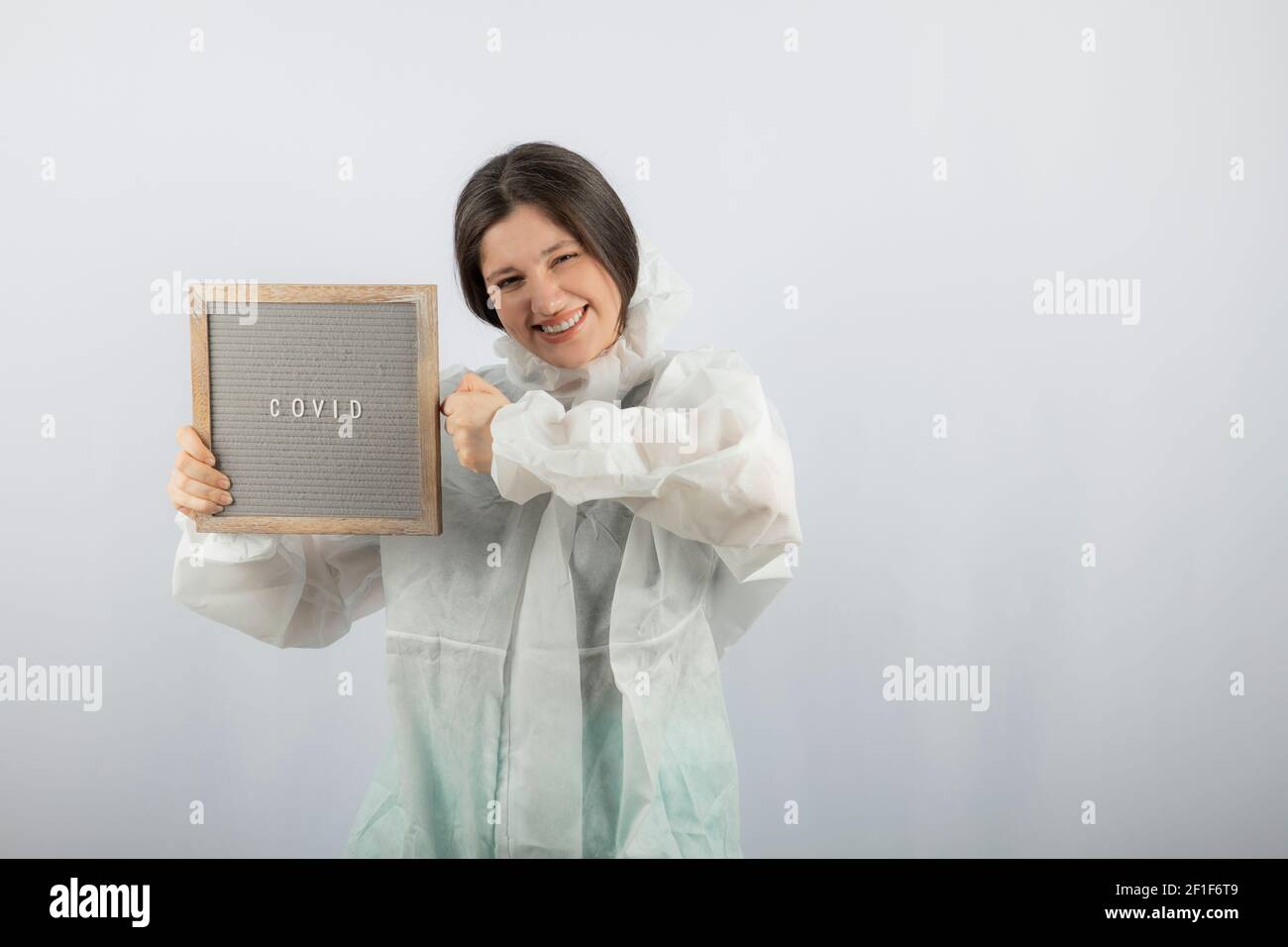 Photo d'un modèle de jeune fille en blouse de laboratoire défensive sur un mur blanc Banque D'Images