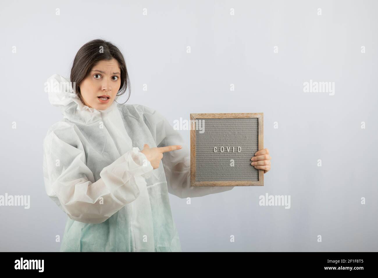 Photo d'un modèle de jeune fille en blouse de laboratoire défensive pointant vers un cadre Banque D'Images