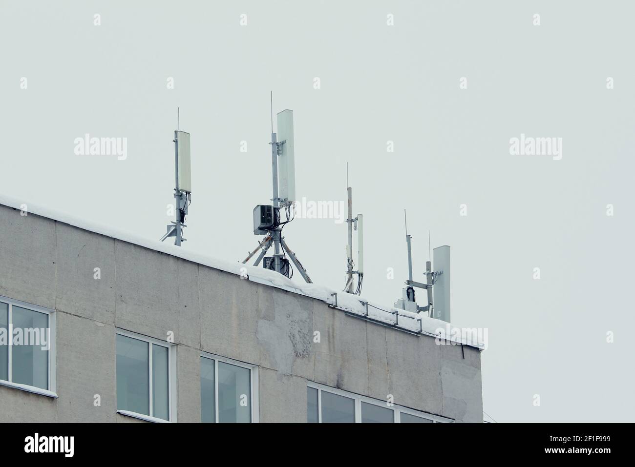 Antenne de réseau mobile de la station de base sur un toit d'un immeuble résidentiel contre un ciel gris. 3g, 4g, 5 g. Photo avec espace vide pour le texte et le design. Banque D'Images