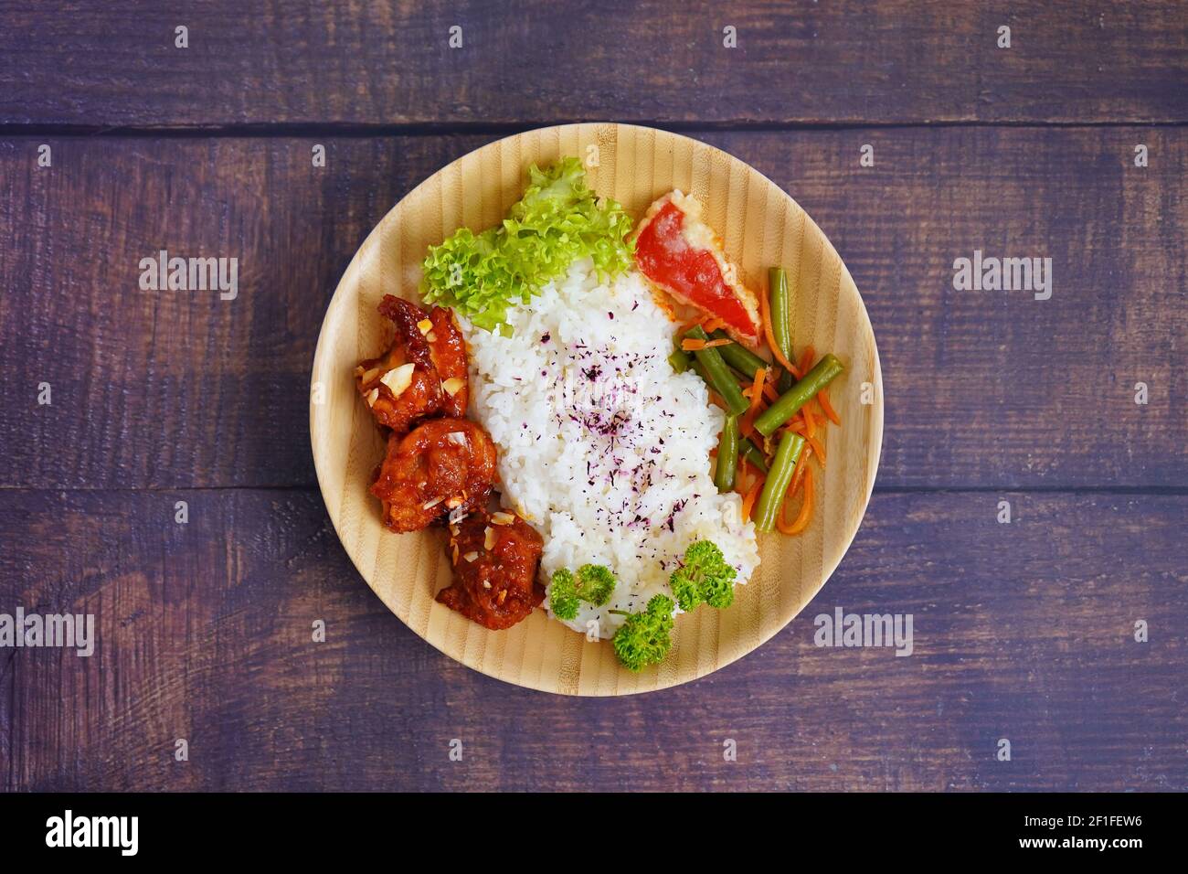 Plat de poulet grillé japonais maison avec légumes et riz, servi sur une assiette de bambou. Arrière-plan de table en bois rustique. Banque D'Images