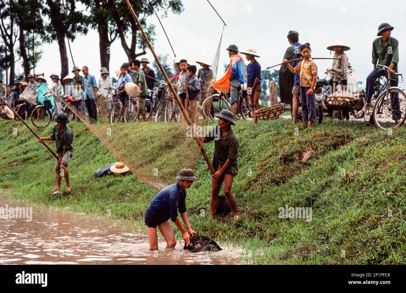 Villageois qui pêchent dans les étangs à poissons avec filets et paniers de pêche, dans les zones rurales du sud du Vietnam, juin 1980 Banque D'Images