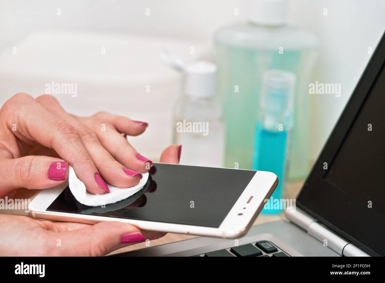 Femme nettoyant téléphone portable avec tampon en papier de coton, essuyant  écran noir, détail gros plan. Flacons flous et clavier d'ordinateur  portable en arrière-plan Photo Stock - Alamy