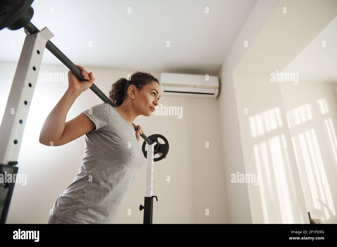 Belle femme s'entraîner avec un barbell à la maison. Concept de mode de vie actif et sain Banque D'Images