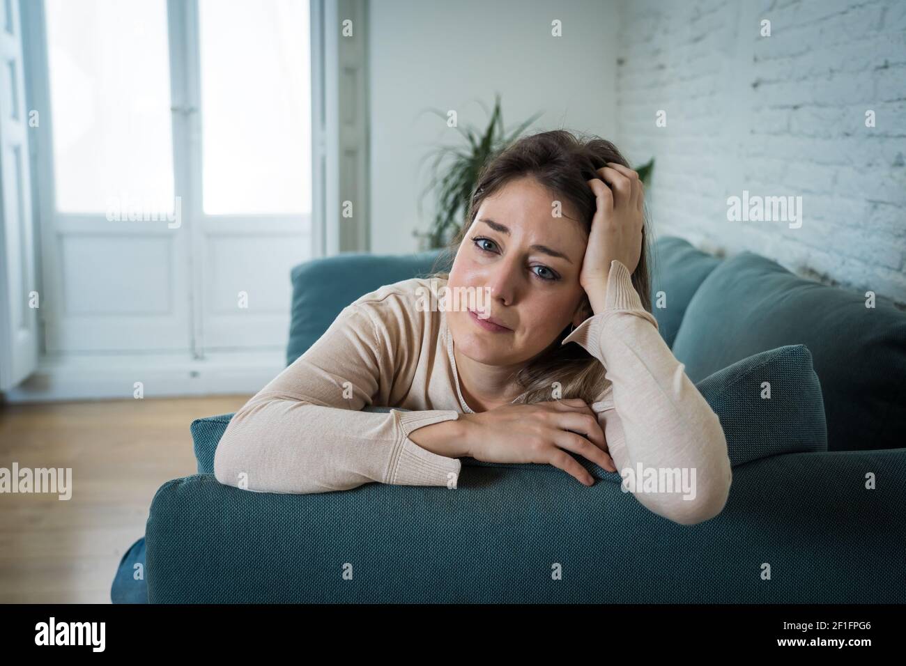 Femme attractive triste et dépressive qui pleure sur un canapé-lit à la maison se sentant seule fatiguée et inquiète souffrant de dépression en santé mentale, solitude et iso Banque D'Images