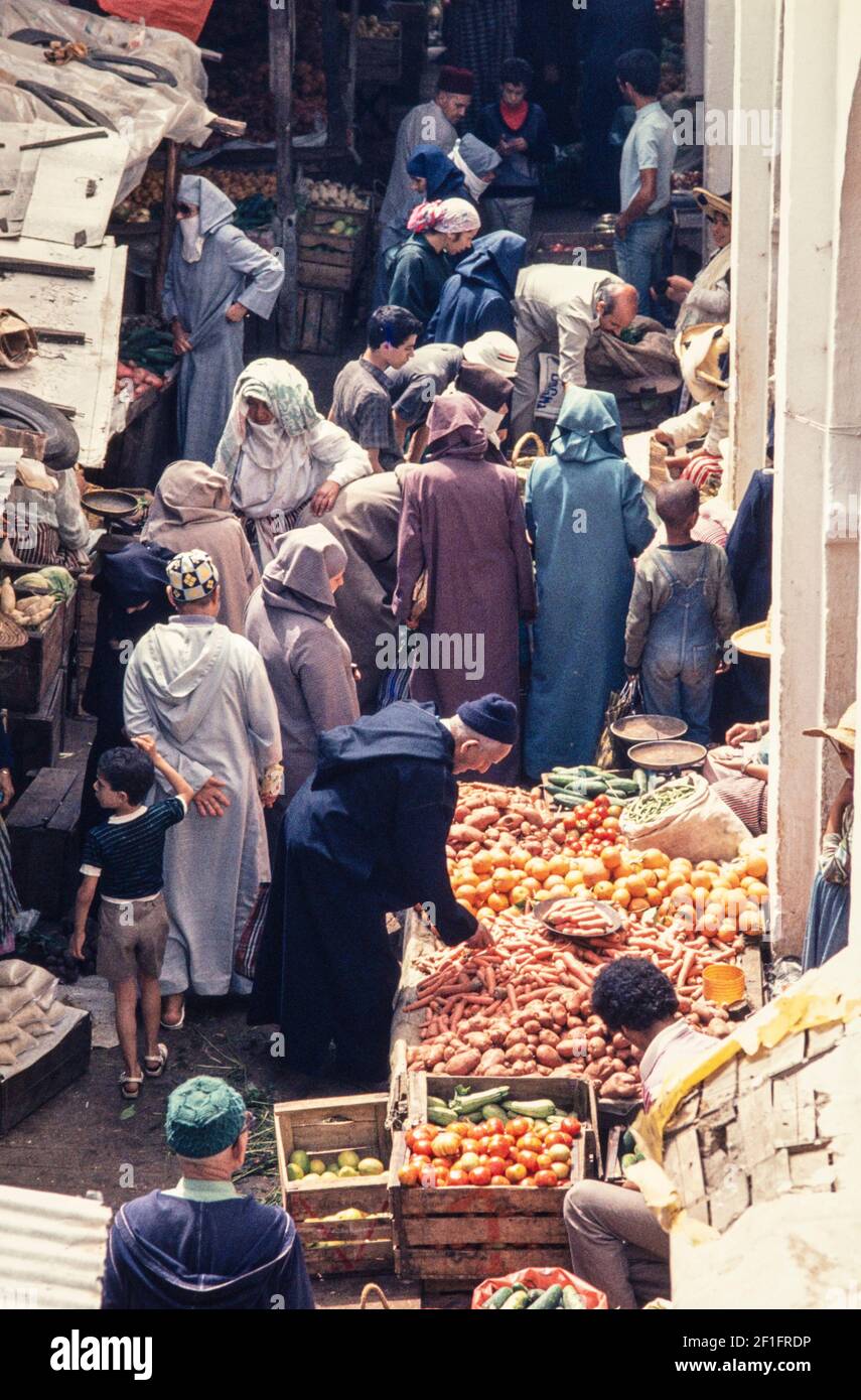 1988 Tunis - Street Scene, Tunis beaucoup de tunisiens achètent des fruits et des légumes des étals du marché dans une rue étroite de la Médina et Souk région de Tunis, Tunisie, Afrique du Nord Banque D'Images