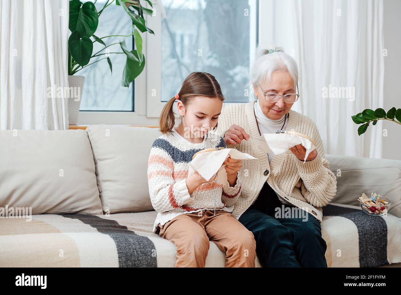 Une petite fille de sept ans et sa grand-mère à cheveux gris de soixante-dix ans, ensemble, sont passionnées par la broderie. Banque D'Images