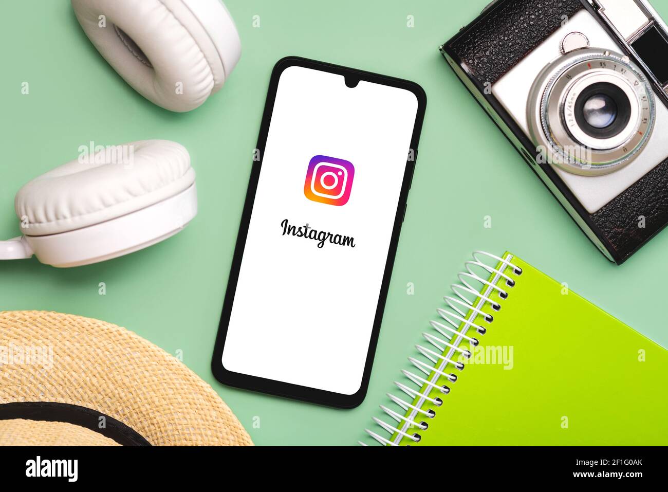 Icône de l'application Instagram sur écran blanc du smartphone avec du blanc casque sans fil, appareil photo d'époque, chapeau et ordinateur portable sur fond vert Banque D'Images Icône de l'application Instagram sur écran blanc du smartphone avec du blanc casque sans fil, appareil photo d'époque, chapeau et ordinateur portable sur fond vert Banque D'Images