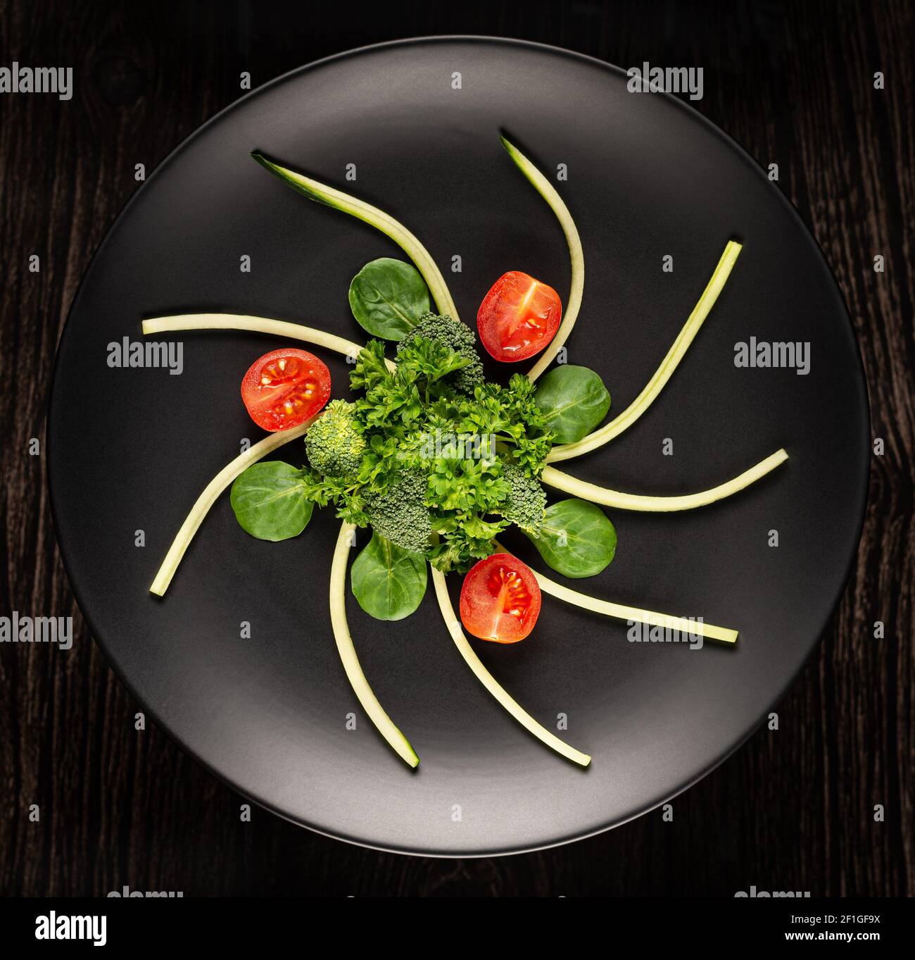 Les légumes en tranches sont sur une assiette noire sur un fond noir photographié. Vue de dessus. Banque D'Images
