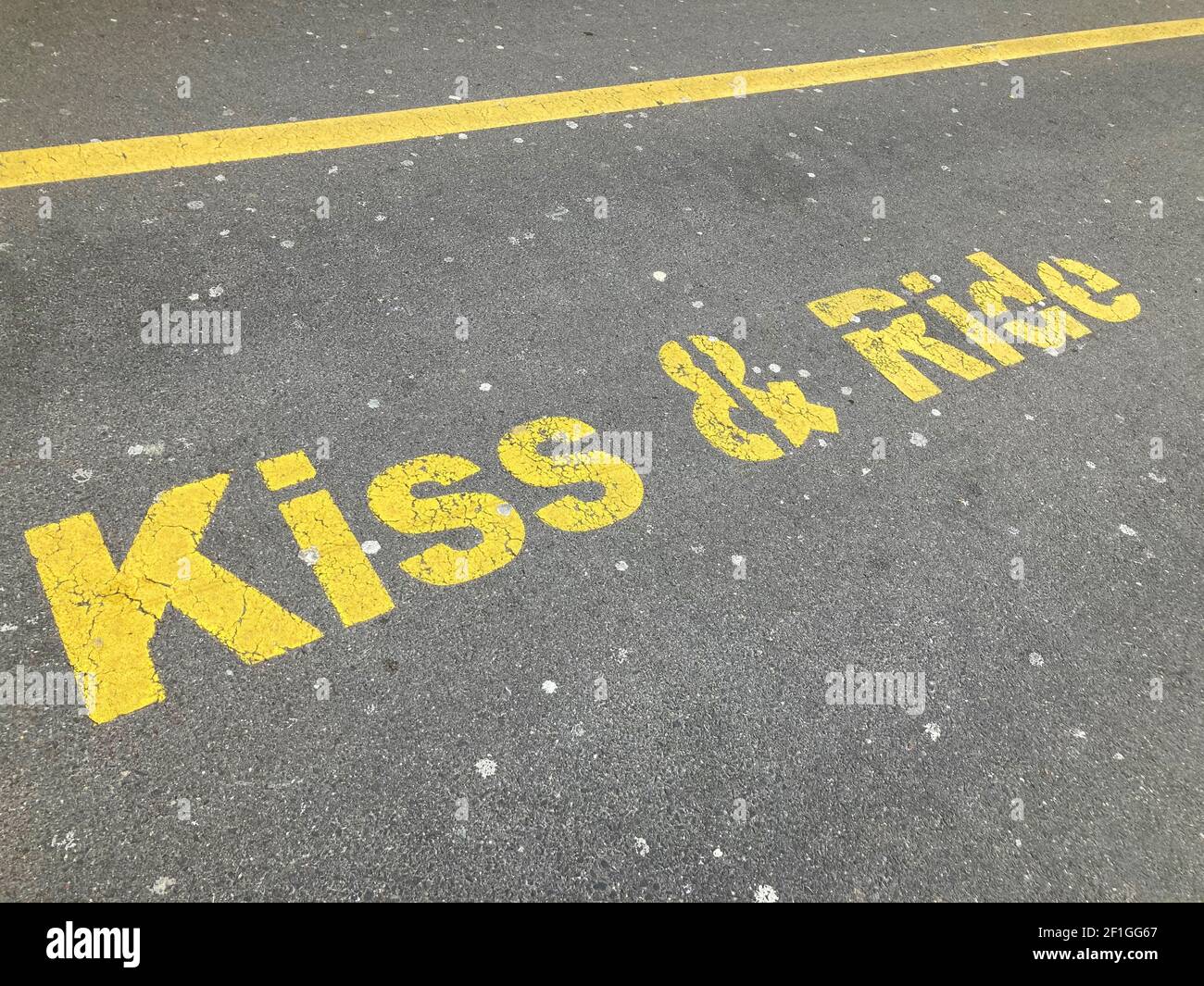 Inscription jaune Kiss and Ride peinte sur l'asphalte à la gare de dépôt à Zug, Suisse Banque D'Images