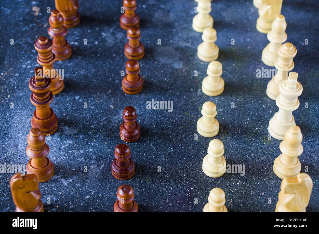 Un gros plan de pièces d'échecs disposées verticalement des deux côtés sur une surface bleue Banque D'Images