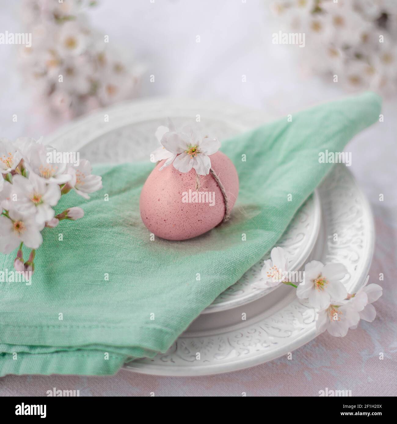 Oeuf de Pâques coloré décoré avec une corde rustique et un ressort fleurs coulées sur une assiette avec des couverts vintage Banque D'Images
