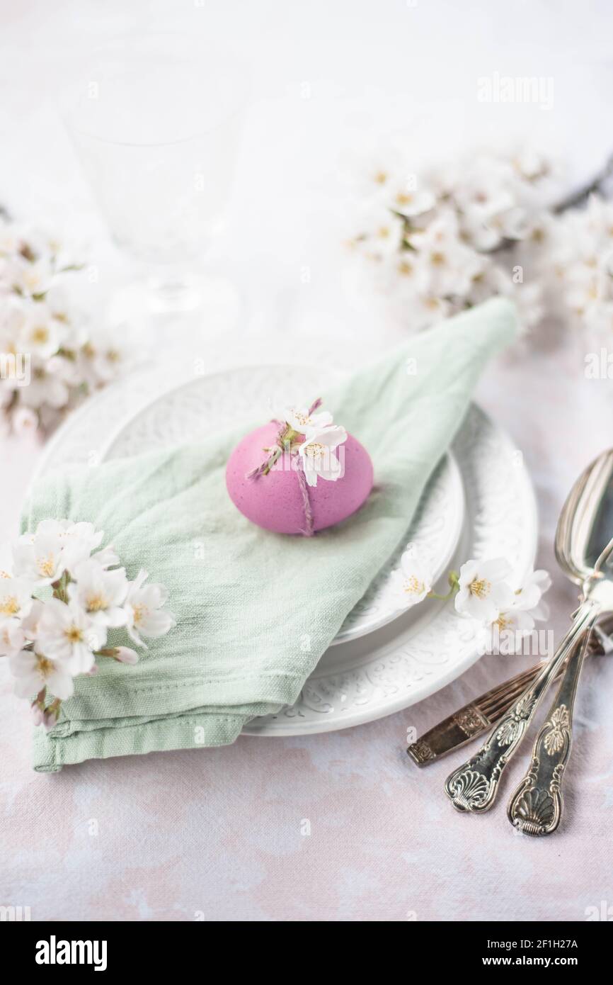 Oeuf de Pâques coloré décoré avec une corde rustique et un ressort fleurs coulées sur une assiette avec des couverts vintage Banque D'Images