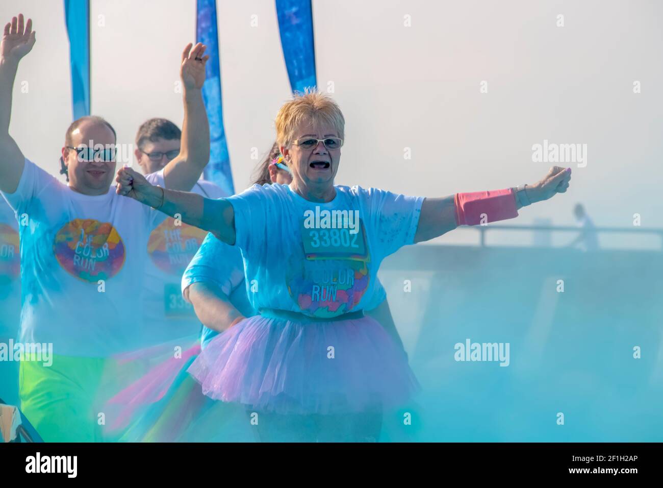4 - 6 - 2019 -Tulsa États-Unis deux coureurs - sur une femme citoyenne âgée dans un tutu et un homme derrière elle - tenez leurs bras comme ils passez à travers la poudre colorée Banque D'Images