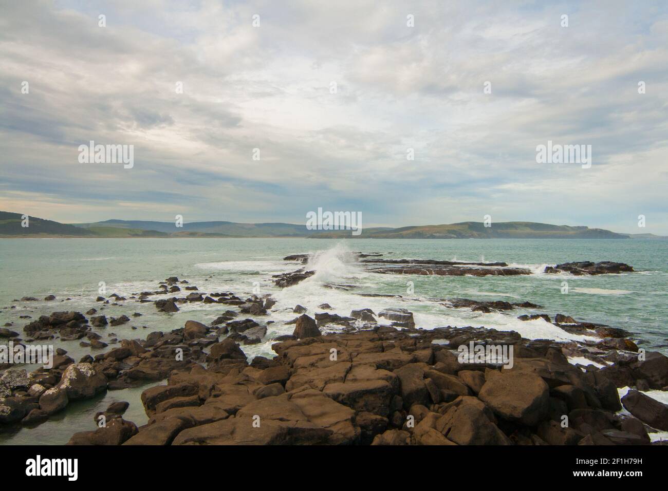 Des vagues sauvages de l'océan Pacifique s'écrasont sur des rochers à l'entrée de la baie de Porpoise, côte rugueuse du sud, Nouvelle-Zélande Banque D'Images