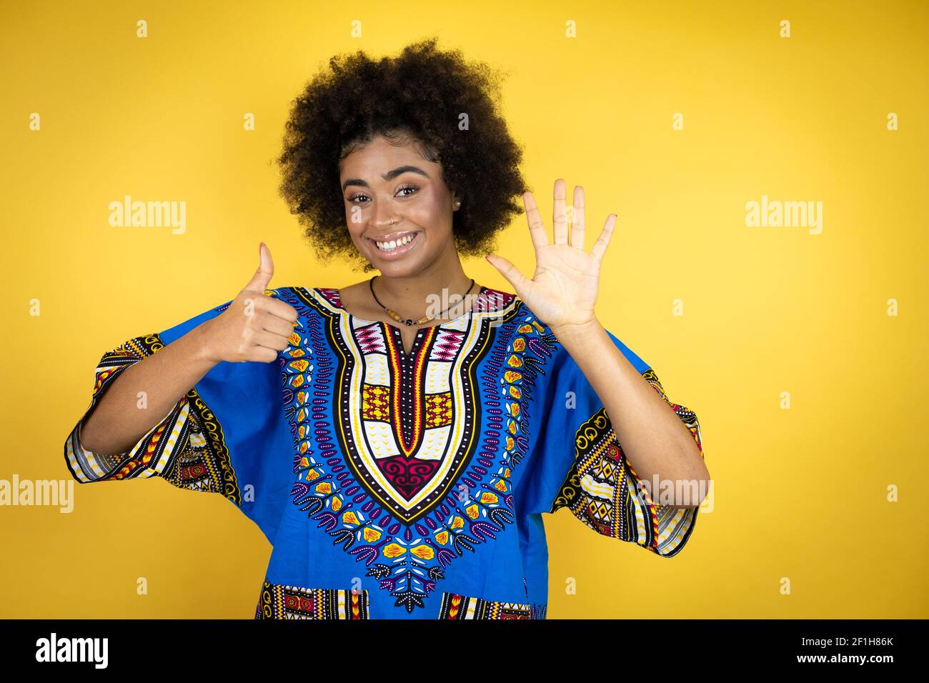 Femme afro-américaine portant des vêtements africains sur fond jaune  montrant et en pointant vers le haut avec les doigts numéro six tout en  souriant confiant et hap Photo Stock - Alamy