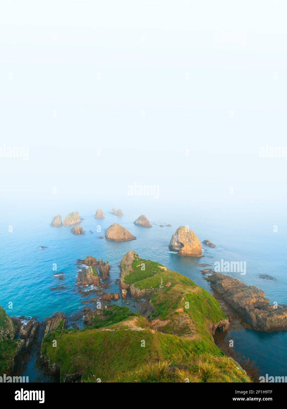Les nuggets, les îlots rocheux emblématiques de Nugget point disparaissent dans la brume blanche abstraite infinie du sud de l'océan Pacifique, la côte des Catlins, au sud Banque D'Images