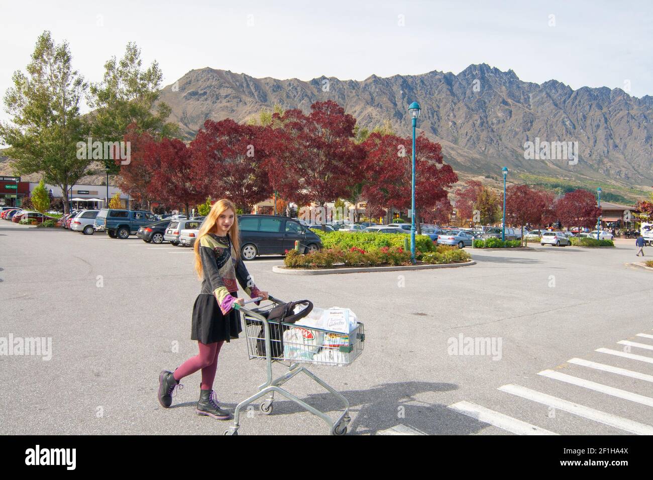 Femme avec un chariot à provisions au centre commercial de Remarkables Park, Frankton, Queenstown, vue sur les montagnes de Remarkables derrière, Nouvelle-Zélande Banque D'Images