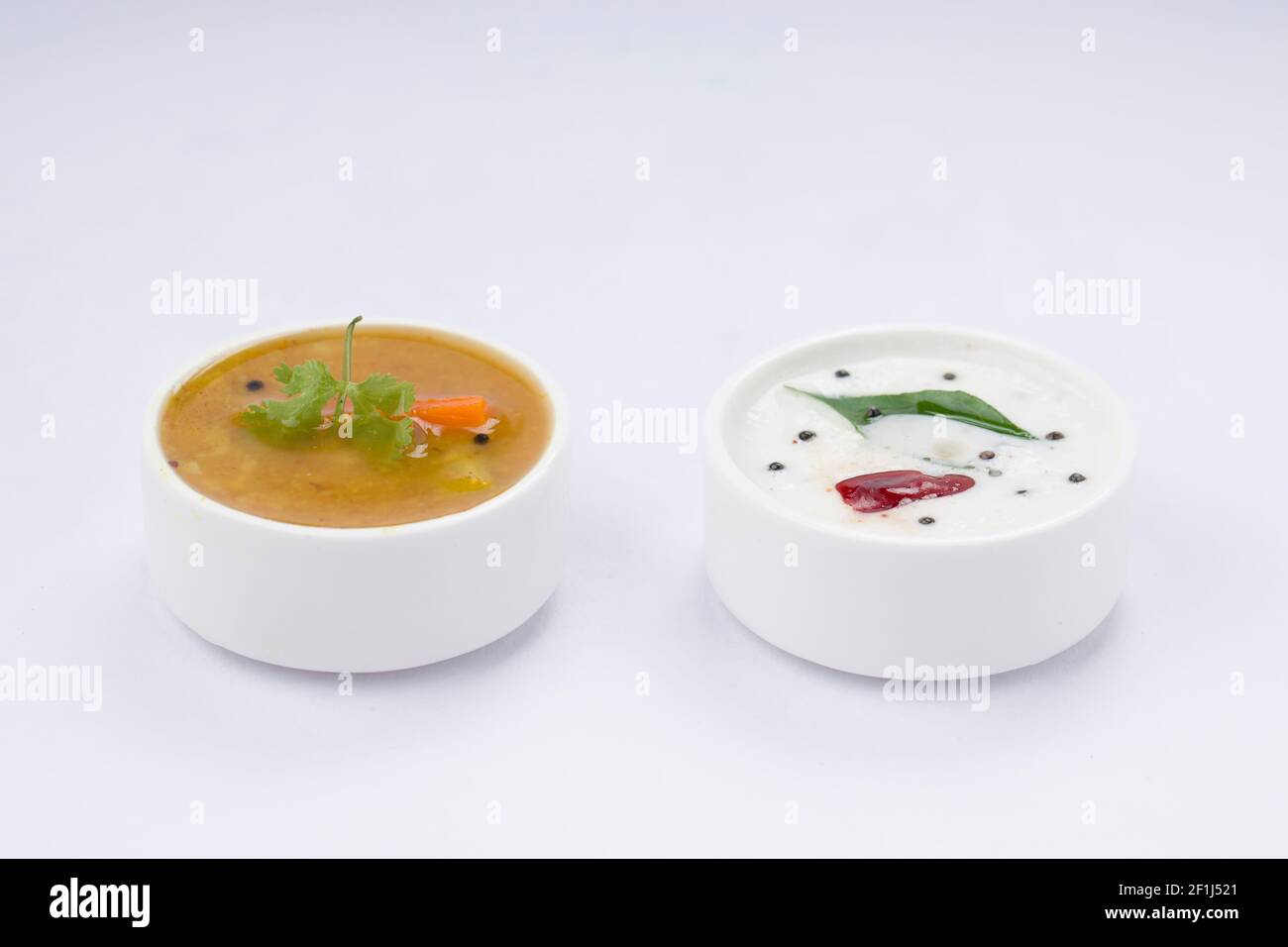 Chutney blanc noix de coco et sambar, disposés dans une table blanche qui est placée sur fond blanc texturé. Banque D'Images