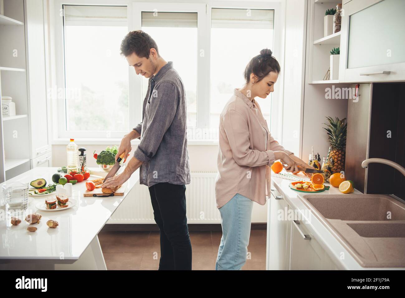 Photo vue latérale d'un couple de caucasiens en coupant des fruits la cuisine ensemble Banque D'Images