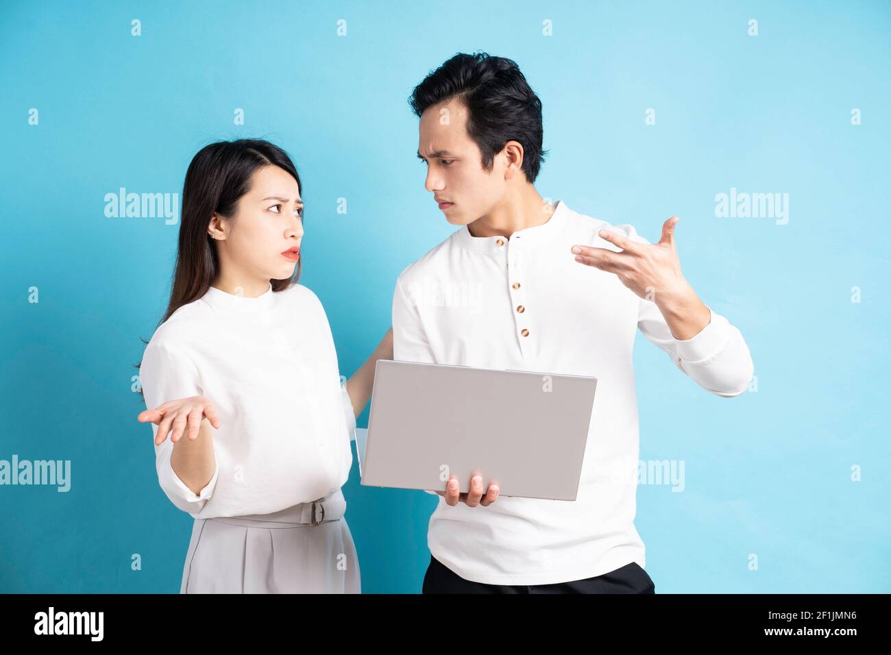 Portrait d'un jeune couple heureux utilisant un ordinateur portable sur fond bleu Banque D'Images