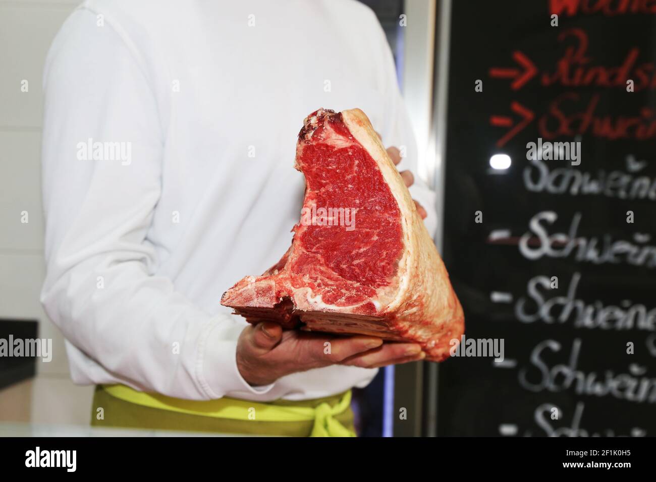 Le boucher tient le steak d'os en T vieilli à la main Banque D'Images