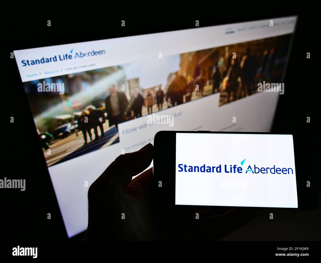 Personne détenant un smartphone avec le logo de la société d'investissement britannique Standard Life Aberdeen plc à l'écran devant le site Web. Mise au point sur l'affichage du téléphone. Banque D'Images