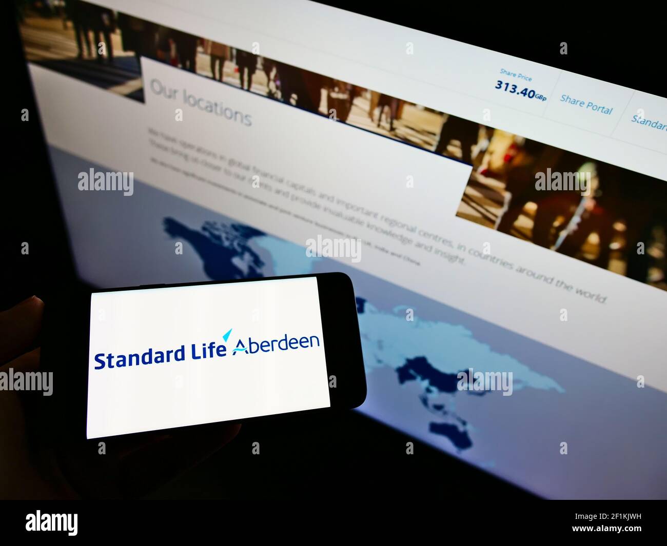 Personne tenant un téléphone portable avec le logo de la société d'investissement britannique Standard Life Aberdeen plc à l'écran devant la page Web. Mise au point sur l'affichage du téléphone. Banque D'Images