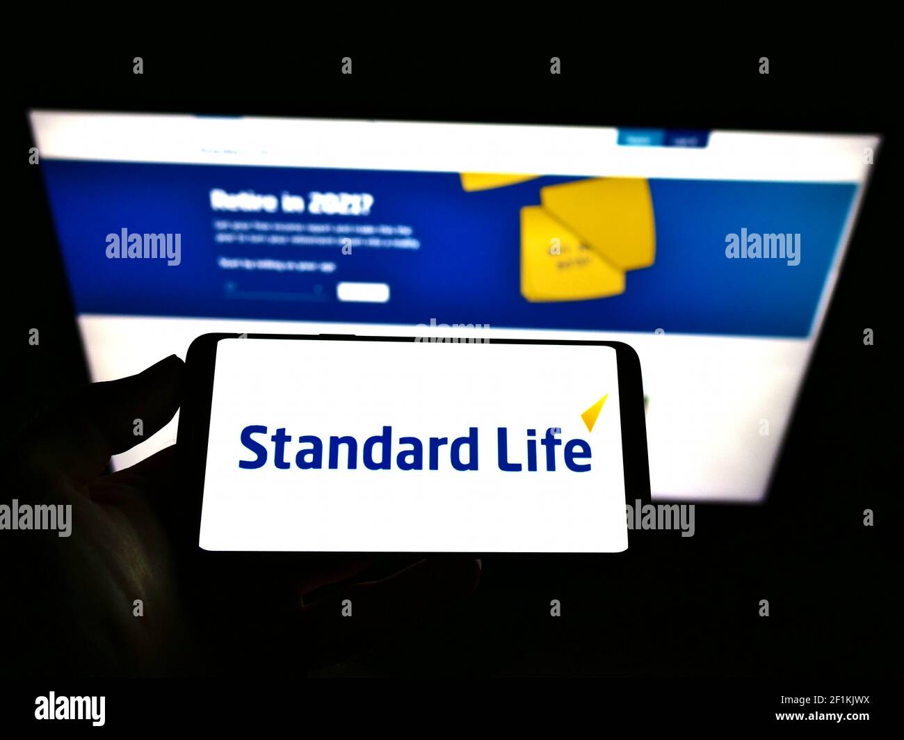 Personne tenant un smartphone avec le logo de la marque britannique d'assurance Standard Life à l'écran devant le site Web. Mise au point sur l'affichage du téléphone. Photo non modifiée. Banque D'Images