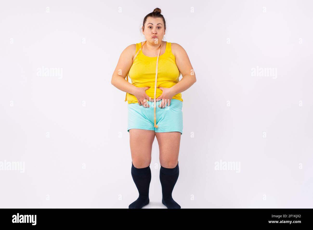 Perte de poids, amincissement, concept de régime. Plus taille, femme XXL  dans les vêtements de maison avec mètre ruban autour de la taille, montrant  l'abdomen gras avec drôle Photo Stock - Alamy