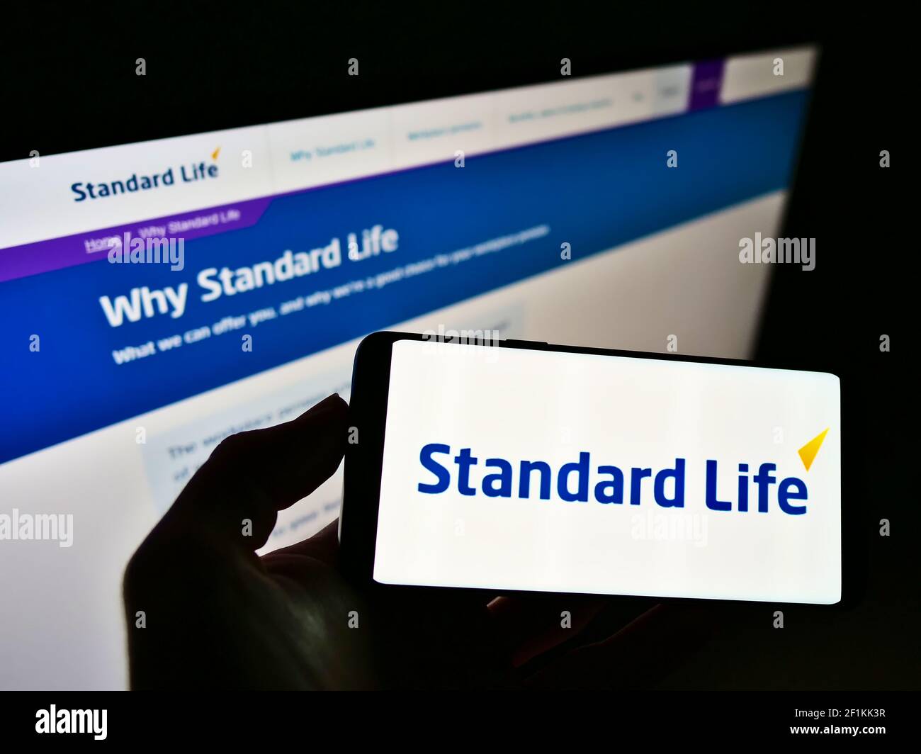 Personne tenant un téléphone portable avec le logo d'entreprise de la marque britannique d'assurance Standard Life sur l'écran devant le site Web. Mise au point sur l'affichage du téléphone. Banque D'Images