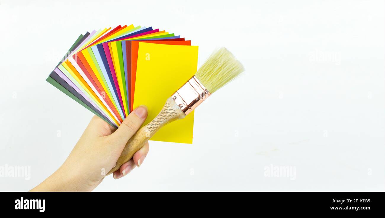 Gros plan du catalogue de peintures avec brosse en bois dans la main de femme, palette de couleurs diverses, échantillons pour la définition de la couleur Banque D'Images