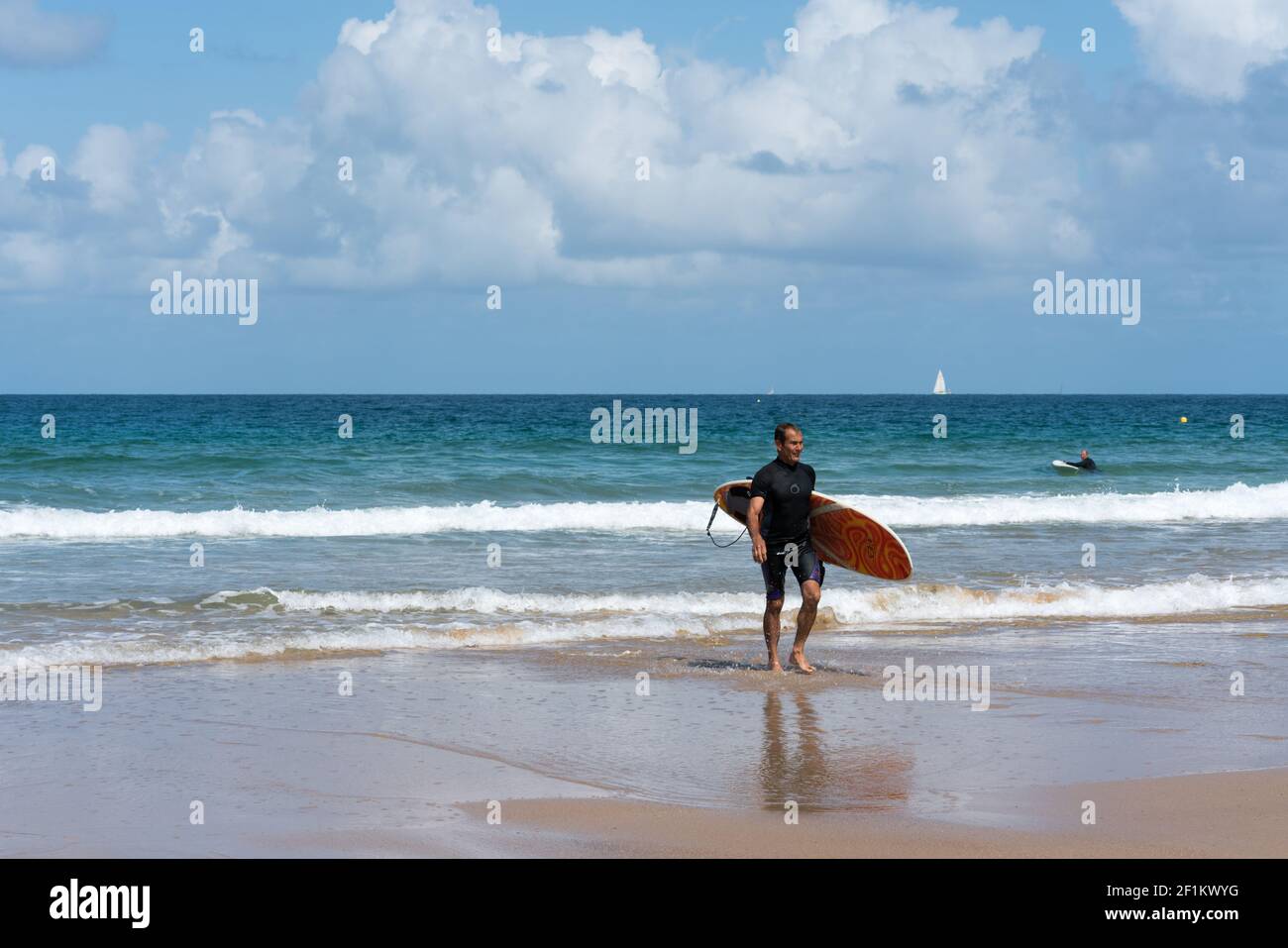 Surfeur d'âge moyen marchant sur la plage après un surf amusant Session dans les vagues sur la côte de BRI Banque D'Images