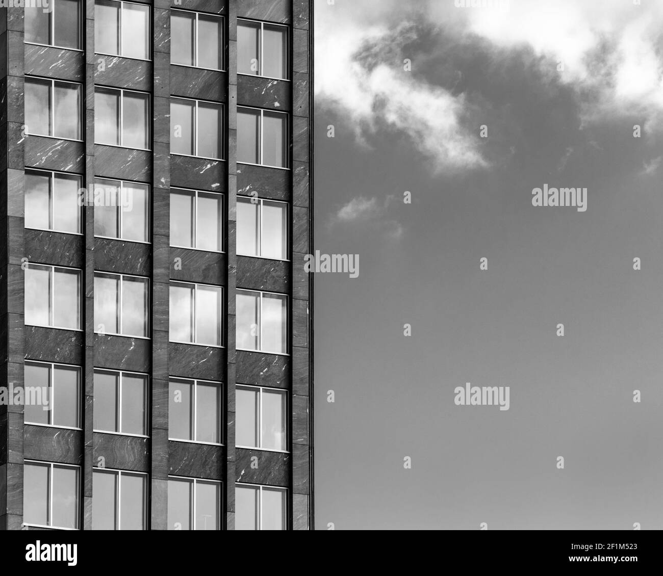 Image en noir et blanc de la façade d'un bâtiment contre un ciel avec des nuages. Banque D'Images