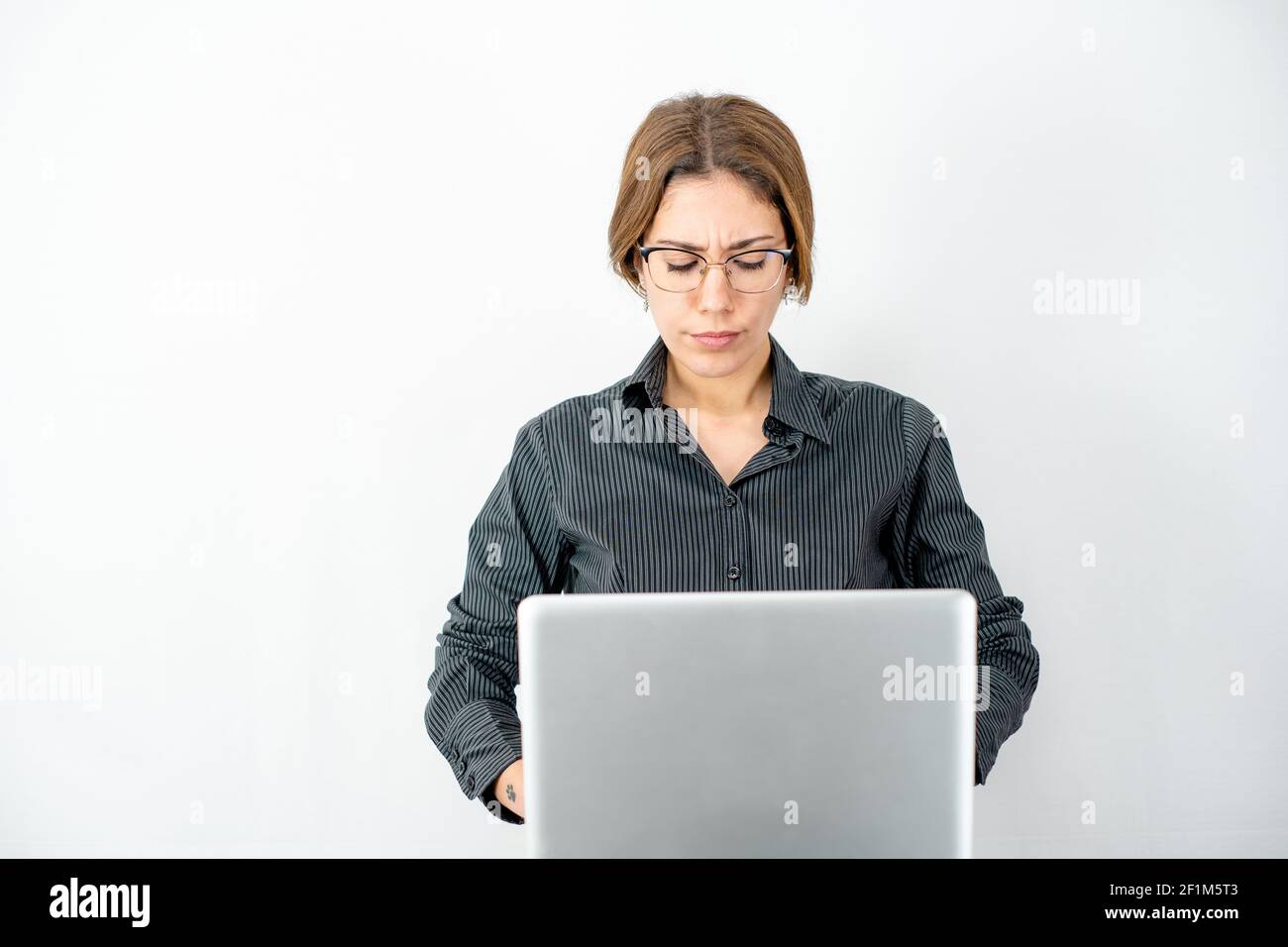 Femme d'affaires avec chemise sombre et verres concentrés sur l'ordinateur le travail regarde l'écran portant des vêtements de travail isolés espace de copie verso blanc Banque D'Images