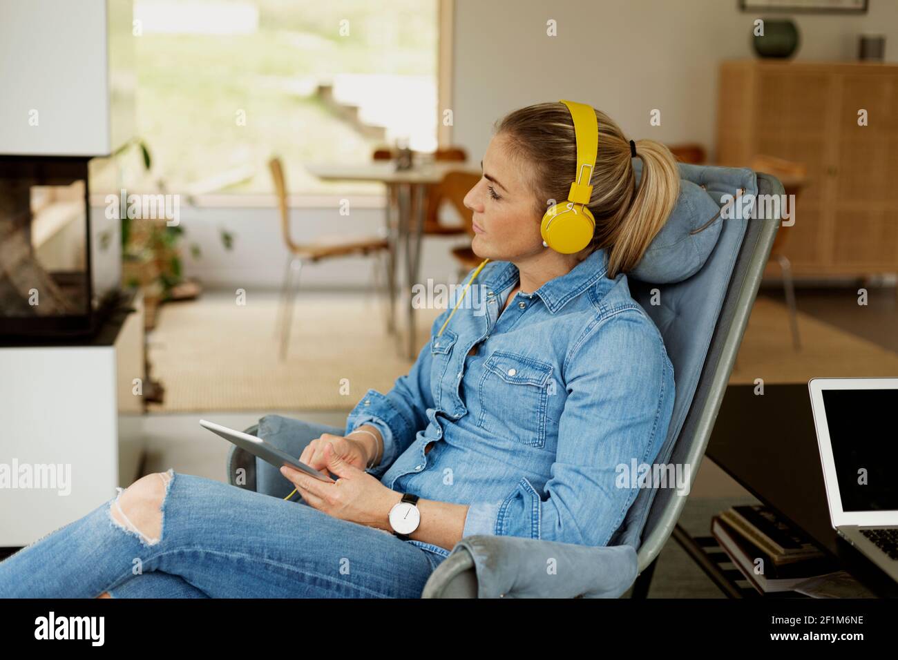 Femme assise dans un fauteuil et utilisant une tablette numérique Banque D'Images
