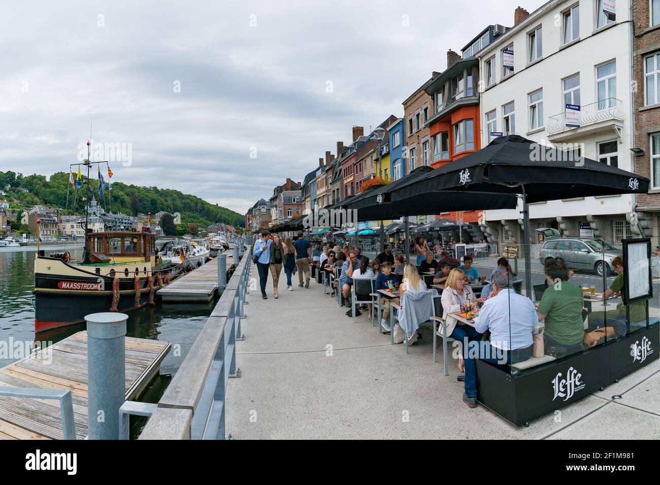 Les touristes apprécient un repas dans les restaurants en bord de rivière De Dinant sur la rivière Maas avec des passants Banque D'Images
